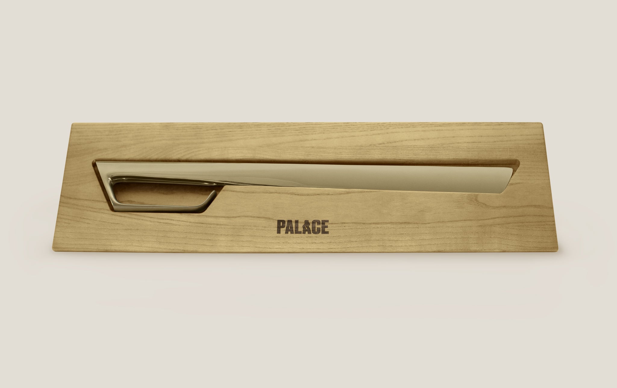 Gold champagne sabre in a light wood case laying on the ground