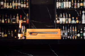 Black champagne sabre in wood case on marble bar