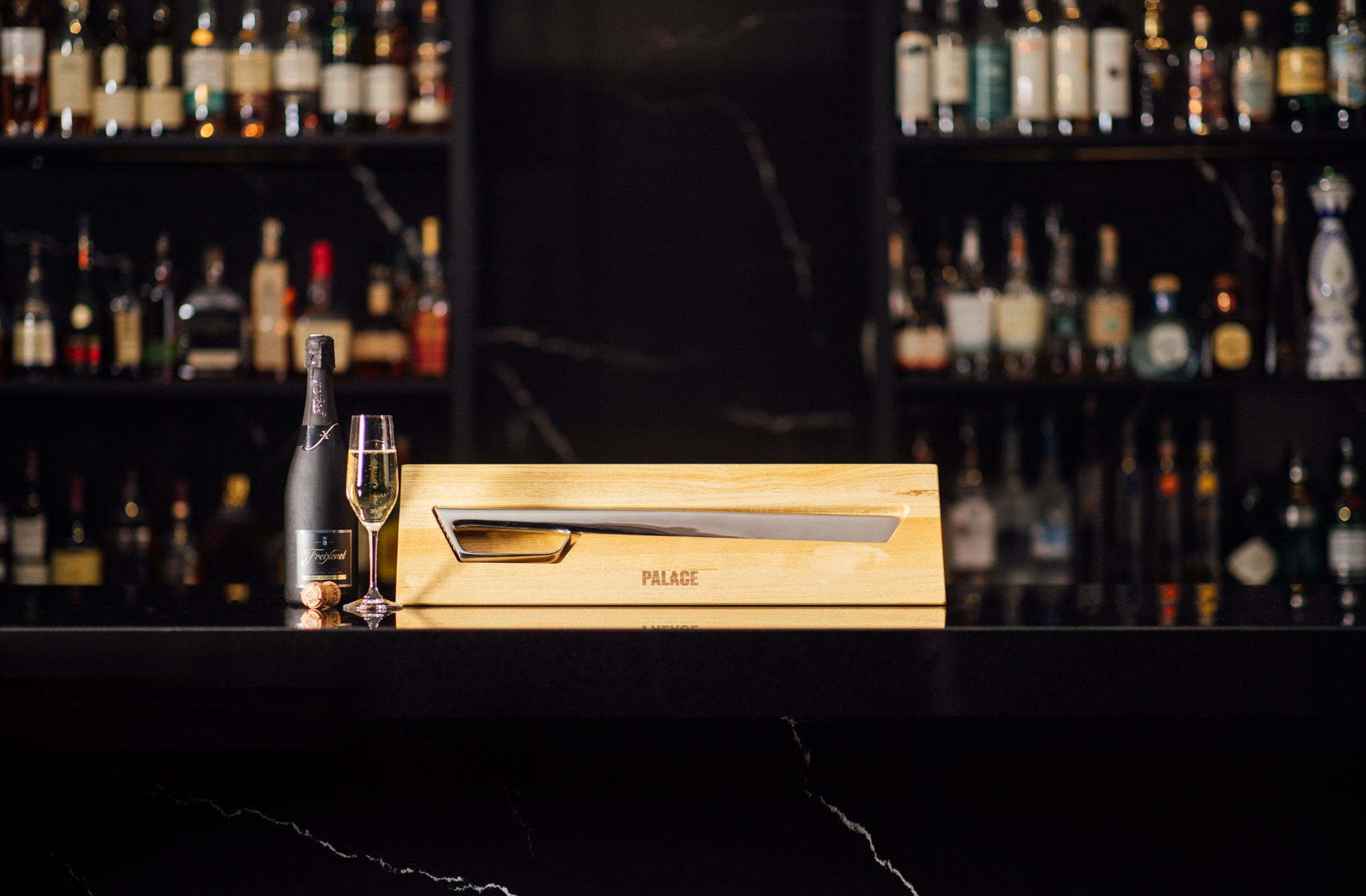 Silver champagne sabre in wood case on marble bar
